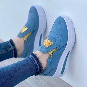Detail of light blue suede sneakers with golden side zipper and 'W' letter patch detail