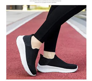 Side view of lightweight black slip-on knit sneakers with white EVA soles on track