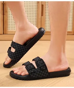 Close-up of men's black double-strap slippers with geometric pattern worn on feet in a room