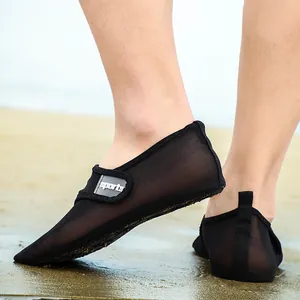 Close-up of breathable black mesh beach water shoes worn on a sandy beach