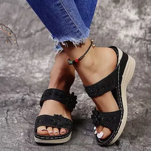 Detailed view of the black flower decorations and rhinestones on woman wedge sandals