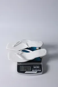Macro view of white kitten heel thong sandals placed on a digital scale for weight check.