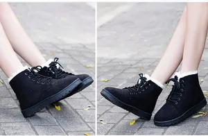 Close-up of black lace-up winter ankle boots with thick white faux fur lining