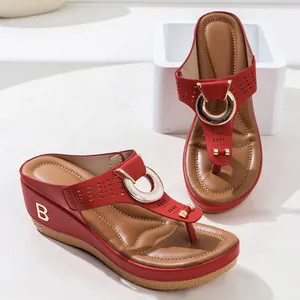 Detailed view of red wedge thong sandals with golden B logo and buckle detail