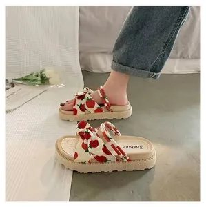 Close-up of women's platform sandals featuring cute strawberry print and bow detail.