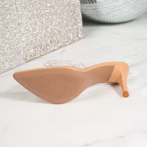Detail view of a nude high heel mule sole featuring a pearl-embellished clear strap