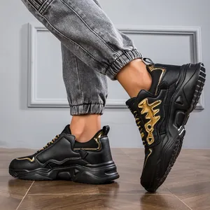 Close-up side view of stylish black and gold chunky dad sneakers worn on a model.