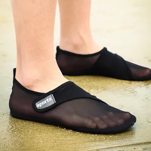 Detailed macro view of breathable black mesh water shoes worn on a sandy beach