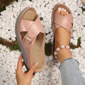 Close-up of pink cross-strap platform sandals with golden buckle on white stones