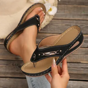 Detalle de sandalias de cuña negras para mujer con hebilla dorada y pespuntes