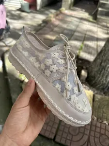 Detail view of cream mesh casual shoes featuring white floral embroidery and laces