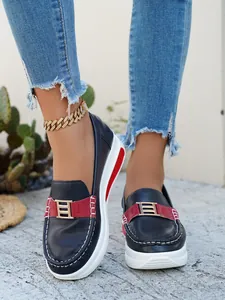 Close-up of stylish navy blue platform loafers with red accents and a chic metal buckle.