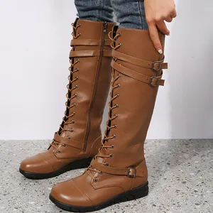 Side detail of brown lace-up knee-high knight boots with buckle straps and flat heel.