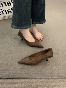 Elegantes zapatos trenzados marrones de punta fina y tacón bajo sobre alfombra