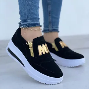 Detail view of women's black platform loafers featuring gold zipper and M logo