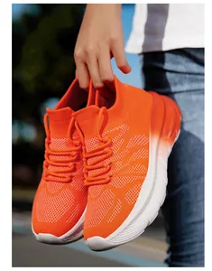 Detail of vibrant orange breathable fly-knit sneakers with comfortable thick sole