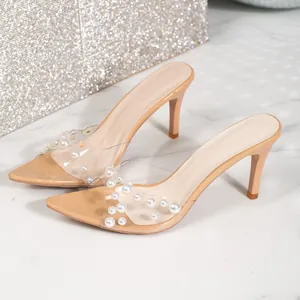Detailed view of nude stiletto mules with pearl-embellished transparent strap