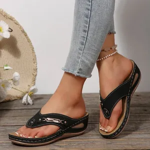 Primer plano de sandalias de cuña negras para mujer sobre fondo de madera rústica