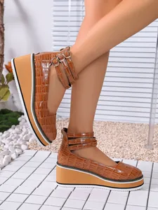 Détail de chaussures compensées en cuir verni à motif crocodile et bride cheville