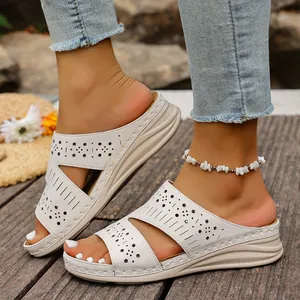 Detail shot of women's white platform wedge sandals with laser-cut decorative patterns.