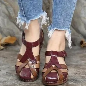 Close-up of vintage burgundy and tan leather cross-strap wedge sandals worn on feet