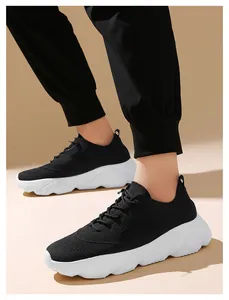 Close-up of lightweight black fly-knit sneakers with chunky white soles on a model