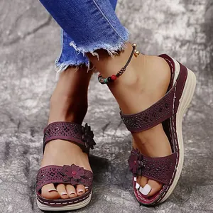 Detail of comfortable burgundy wedge sandals with elegant flower and rhinestone decor