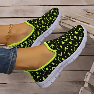 Detalle de zapatillas slip-on para mujer con estampado de estrellas y lunas neón