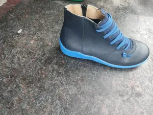 Side view of dark blue leather casual ankle boots with bright blue sole and laces