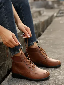 Detail shot of vintage brown lace-up ankle boots worn with denim jeans on stone steps.