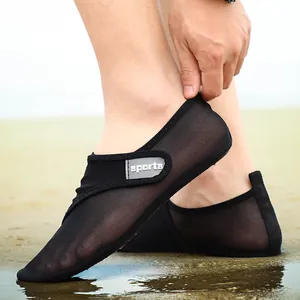 Detail view of breathable black mesh beach water shoes worn on a wet sandy shore