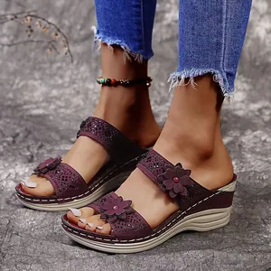 Close-up detail of purple wedge sandals with decorative flowers and rhinestone accents