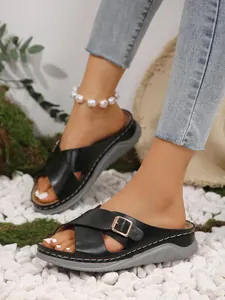 Detailed view of women's black cross-strap slippers with golden buckle and thick grey sole