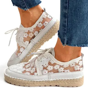 Detailed view of white mesh lace sneakers featuring delicate floral embroidery and laces.