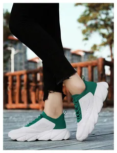 Close-up view of lightweight green and white fly-knit sports shoes worn on a boardwalk.