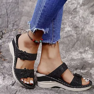 Macro view of black summer wedge sandals featuring floral appliqués and rhinestone details