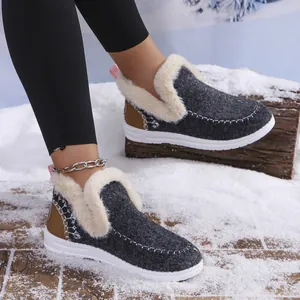 Warm women's gray fuzzy winter slippers with white plush lining in a snowy setting