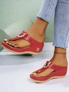 Side view of red wedge flip-flop sandals with gold buckle and metallic B letter logo