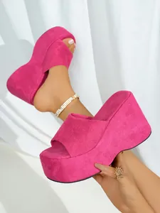 Detailed close-up of vibrant pink platform wedge slippers with soft suede-like fabric