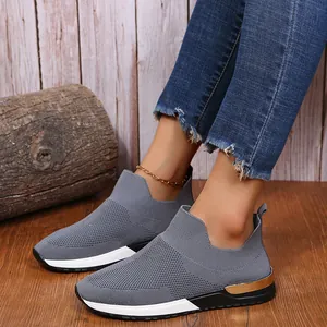 Gros plan de baskets grises fly-knit pour femmes avec détail doré sur sol en bois