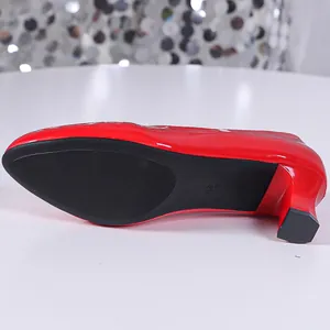 Detailed view of the non-slip black sole and block heel of red patent shoes