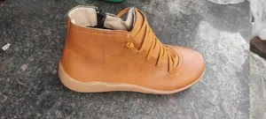 Side view detail of women's tan faux leather ankle boots with side zipper and decorative laces