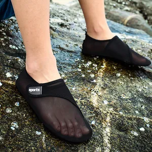 Close-up detail of breathable black mesh beach water shoes being worn on outdoor rocks