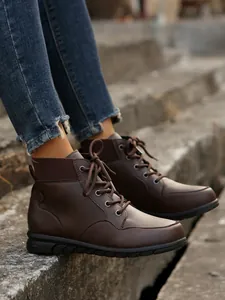 Close-up view of brown vintage lace-up boots on a model sitting on concrete steps