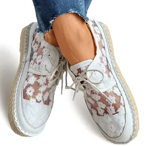 Close-up detail of white mesh lace casual shoes with floral embroidery and jute sole.