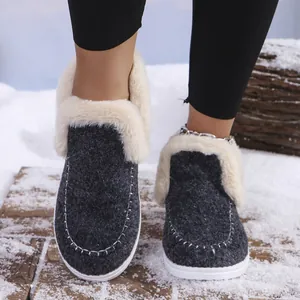 Close-up of warm winter slippers with faux fur lining on a snowy wooden background.