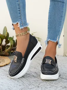 Close-up of black PU platform loafers with decorative gold-tone metal buckle.