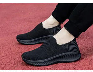 Close-up of black lightweight knit slip-on sneakers on a red track for men and women.