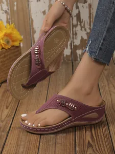 Detail of purple wedge flip-flop sandals with gold accents and decorative stitching