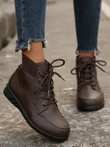 Macro view of women's retro brown lace-up ankle boots with textured knit collar.